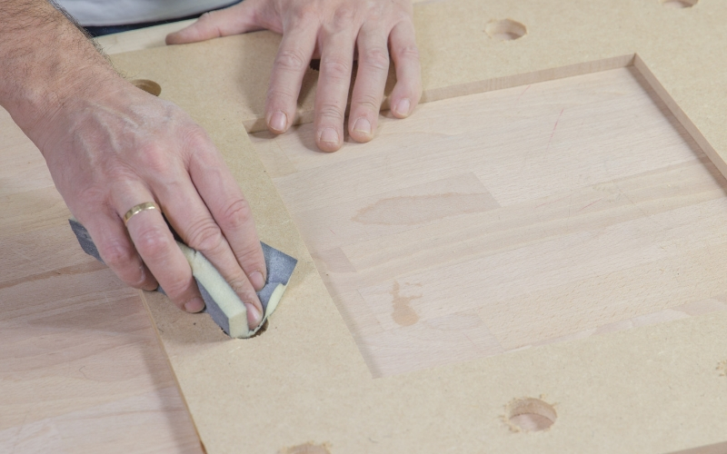 Lija el tablón de madera después de hacer los agujeros