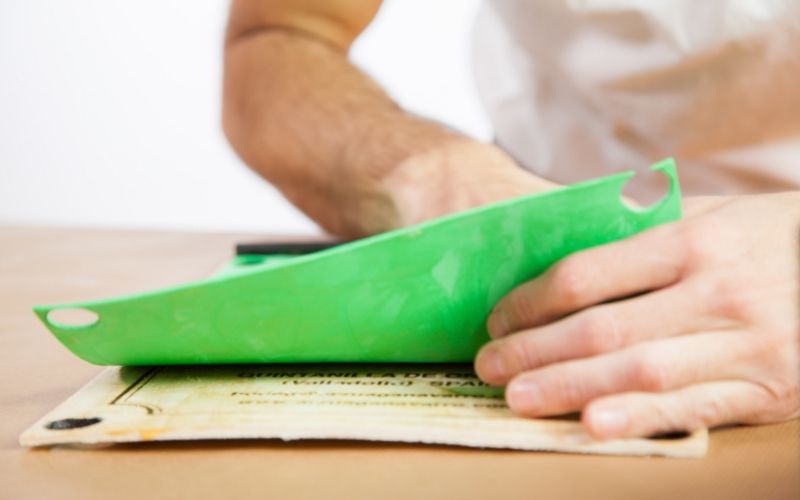 Pega el tapete en la plancha de madera