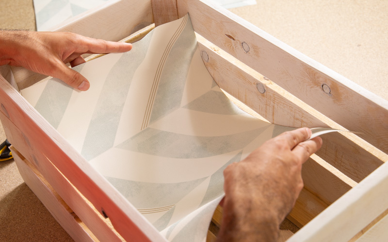 Coloca el papel pintado en las cajas de madera